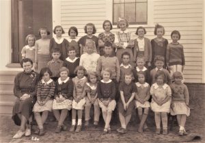 Photo of a school class, 26 students and the teacher, in front of a building 